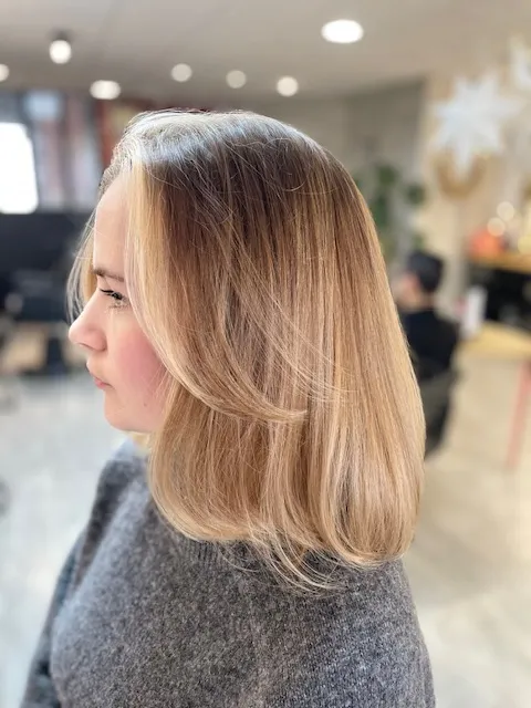 Cheveux blonds mi-longs, lisses et légèrement dégradés.