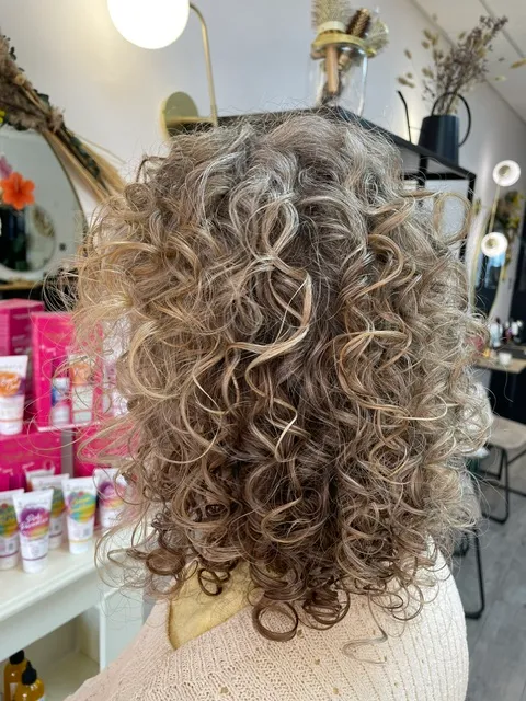 Chevelure mi-longue avec des boucles blondes et brunes bien définies.