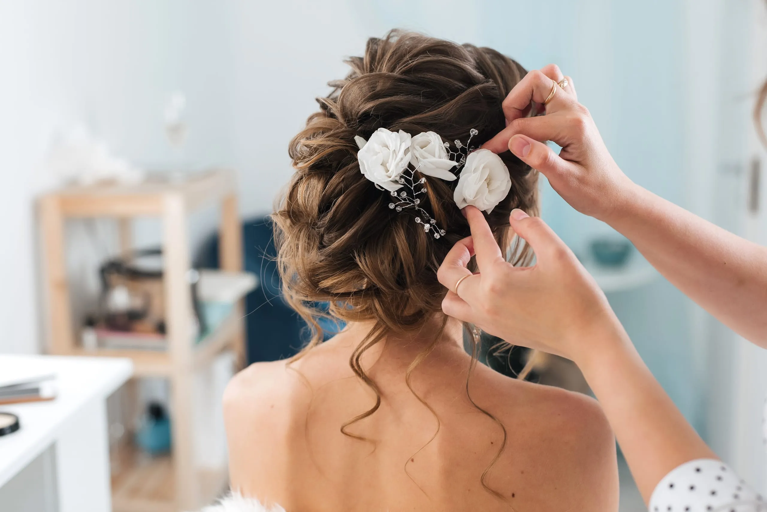Chignon brun décoré de fleurs blanches pour une coiffure événementielle.