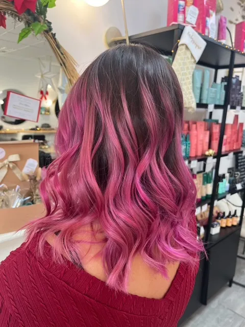 Cheveux mi-longs ondulés avec une coloration rose intense.