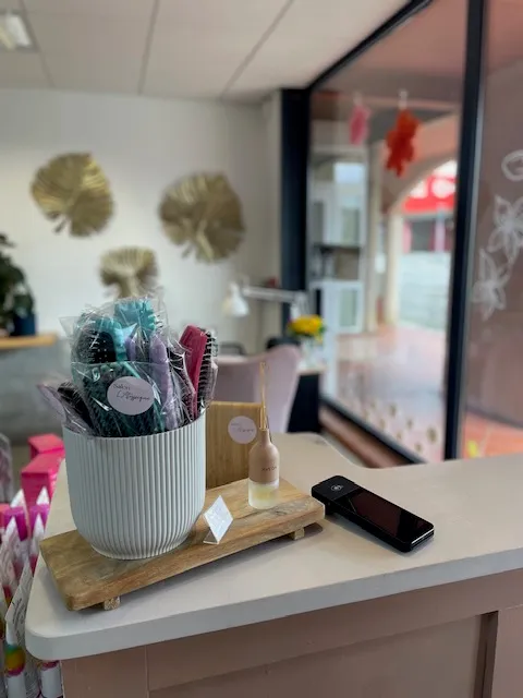 Comptoir d'accueil du salon avec présentoir, terminal de paiement et vitrine donnant sur la rue.