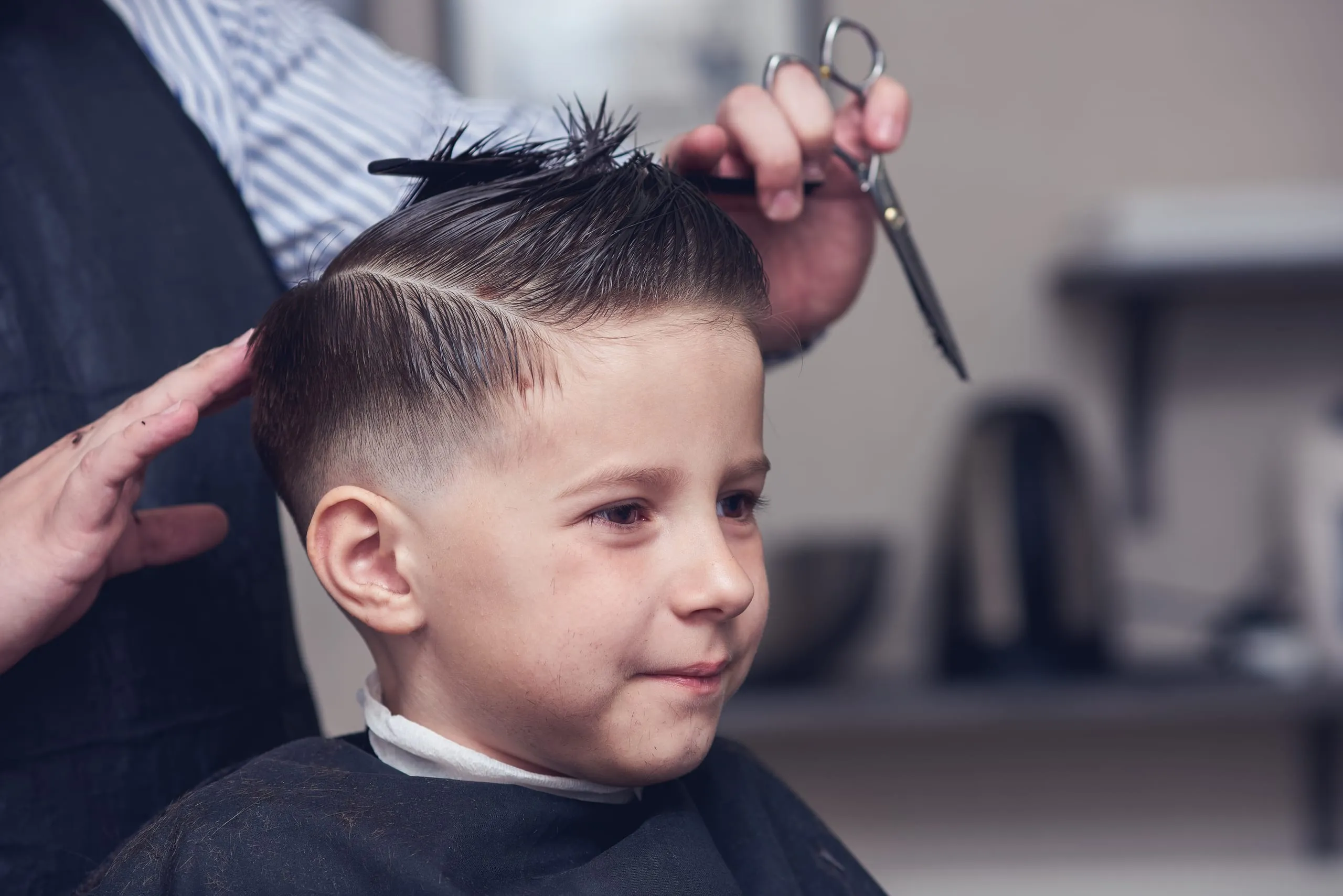 Coupe de cheveux enfant réalisée aux ciseaux dans un salon de coiffure.
