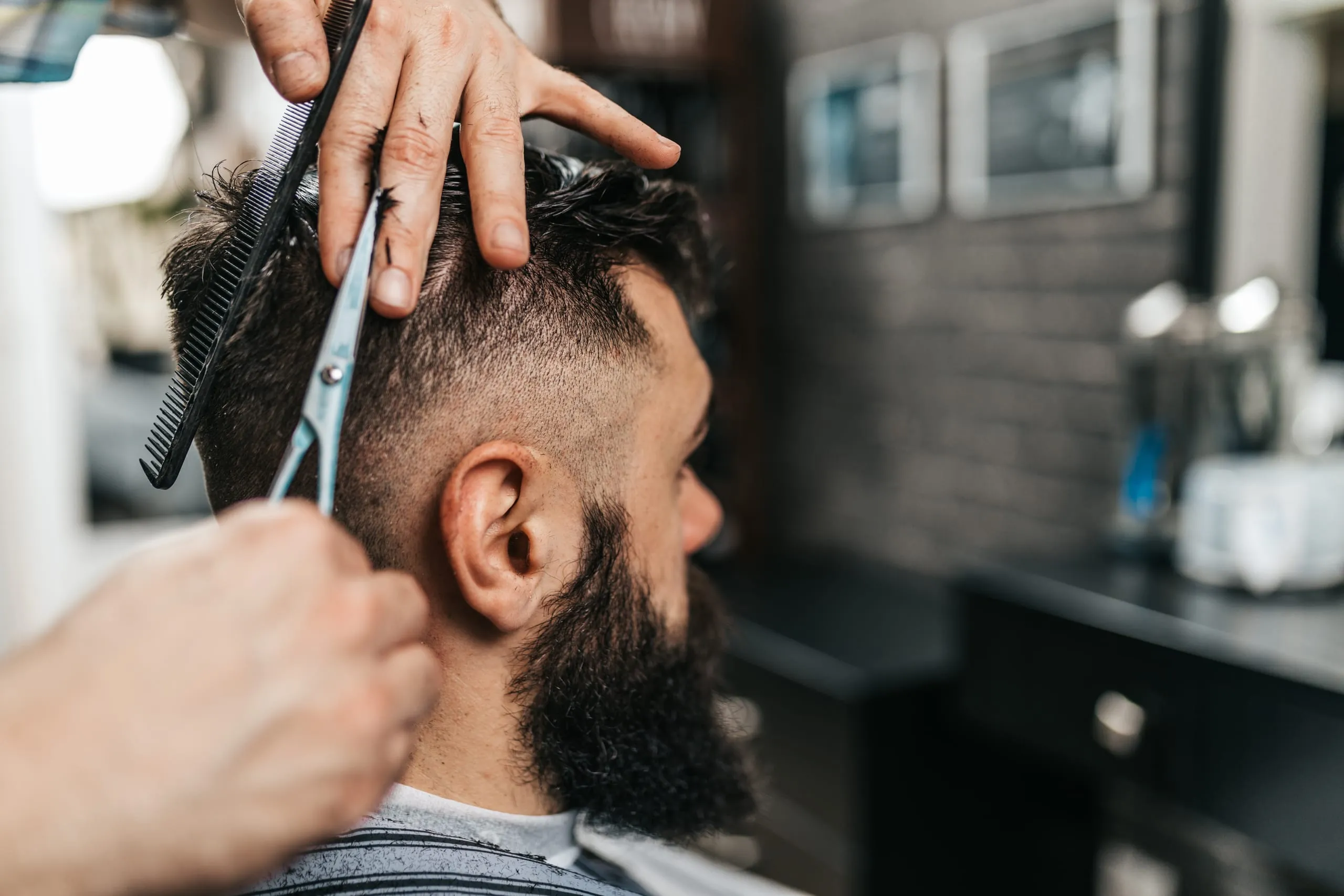 Coupe homme aux ciseaux sur cheveux bruns courts avec un dégradé et une barbe.