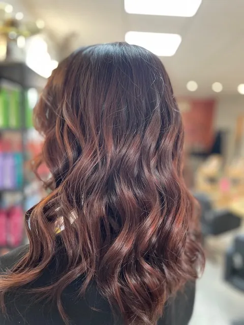 Cheveux longs ondulés dans des nuances brunes cuivrées.